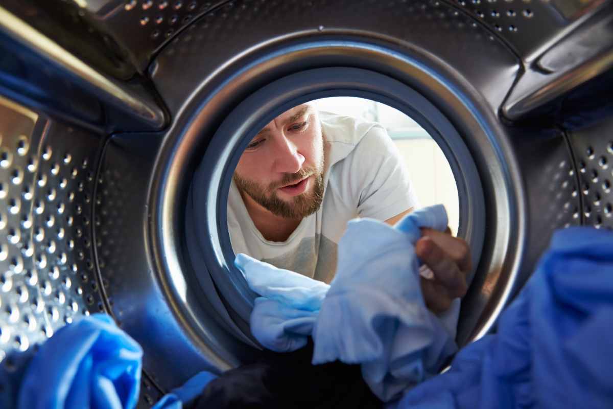 Uomo che guarda una maglia del bucato uscito dalla lavatrice