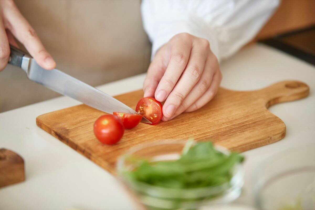 Tagliare i pomodori sul tagliere di legno