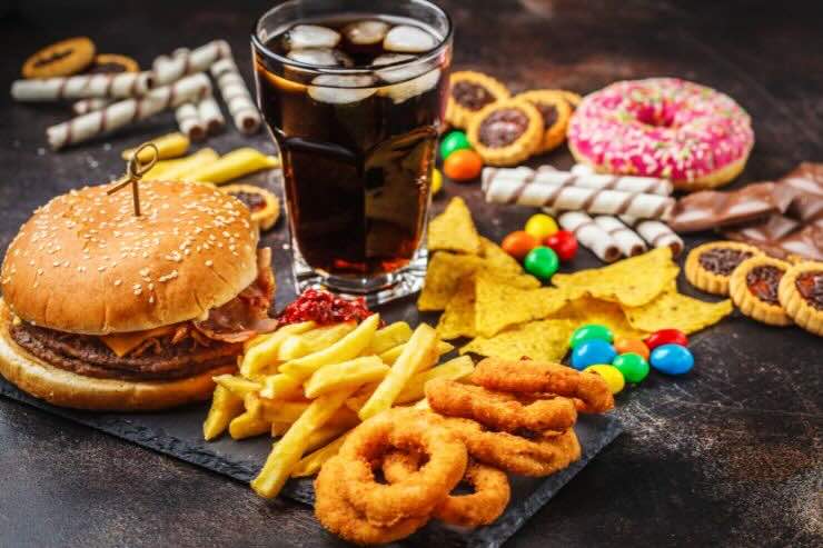 Coca cola, cibo fritto (patatine, anelli di cipolla), hamburger, donuts e altri dolcetti 