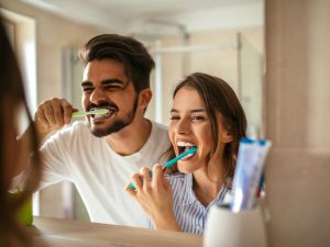 ragazzo e ragazza che si lavano i denti allo specchio