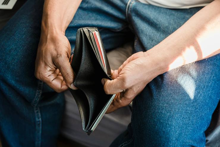 uomo con in mano un portafoglio aperto e vuoto